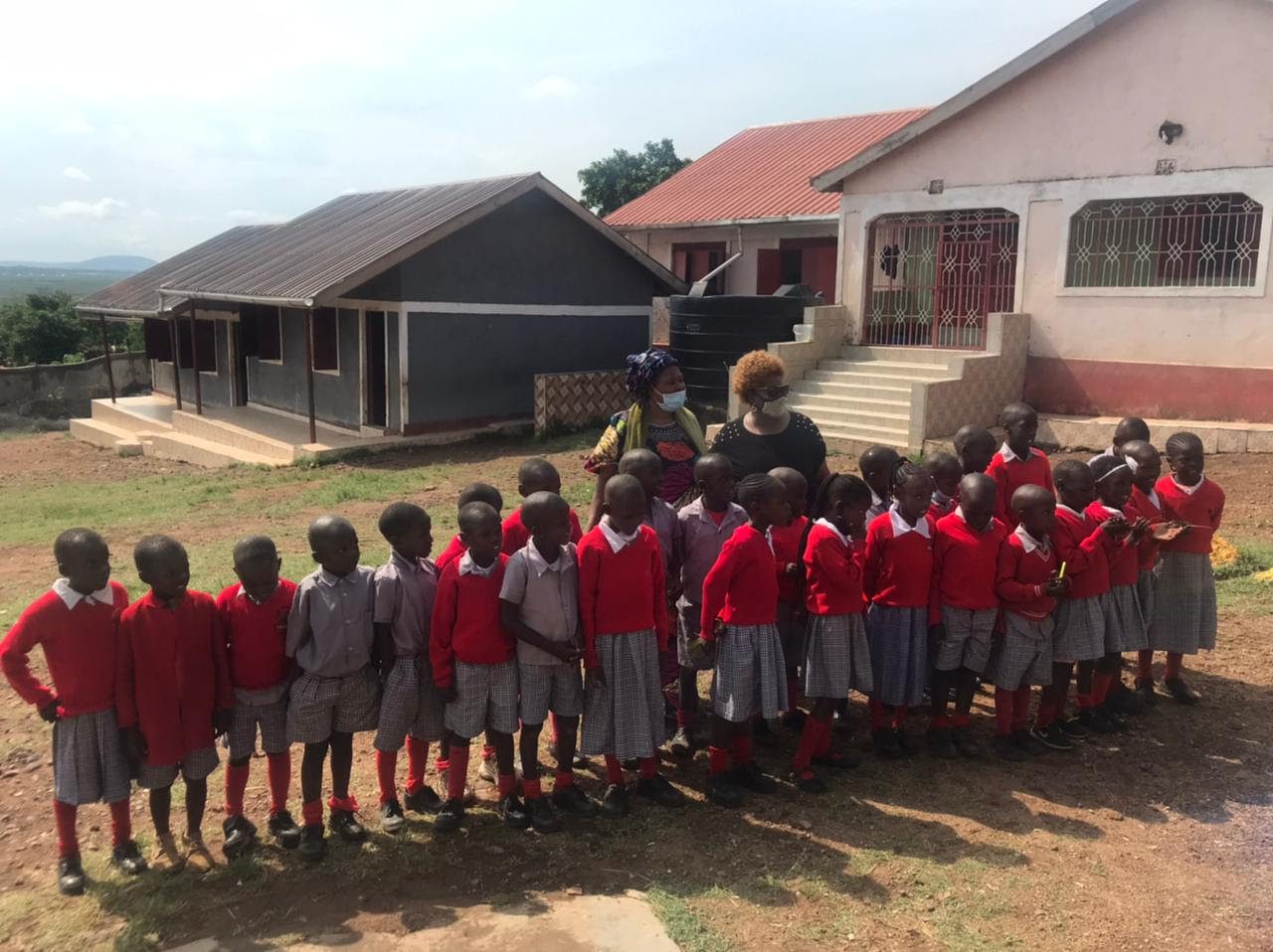 A group of school children posing in front of a house.