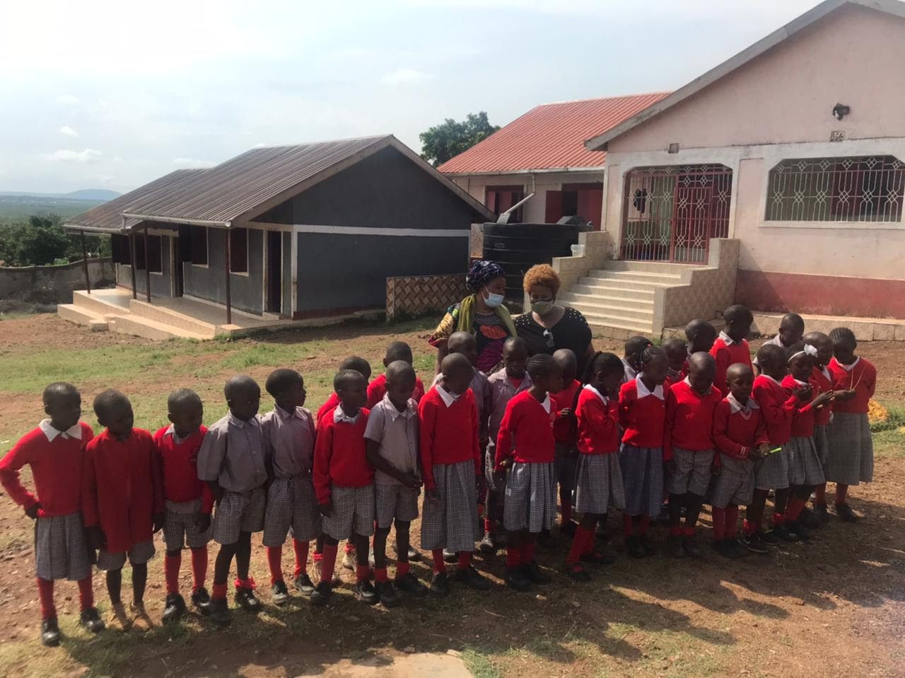 A group of school children standing in front of a house.
