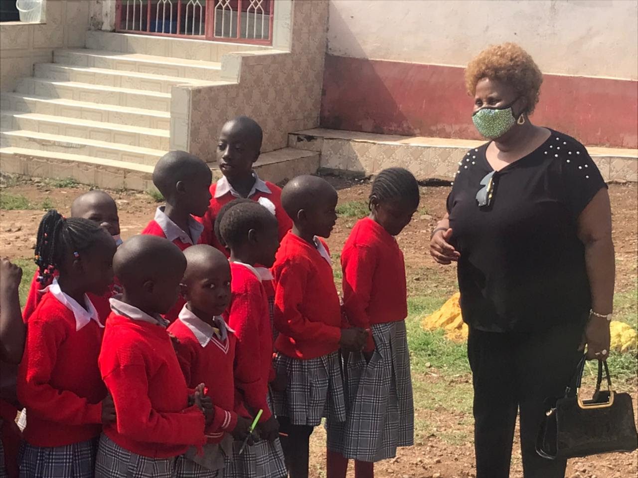 A woman wearing a face mask with a group of children.