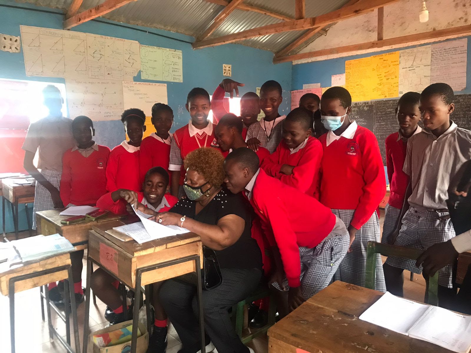 A group of children standing around a desk in a classroom.
