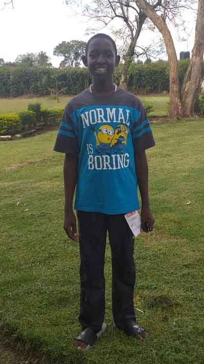 A boy in a blue shirt standing in a grassy area.