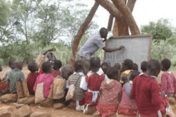 A man teaching children in a village in kenya.