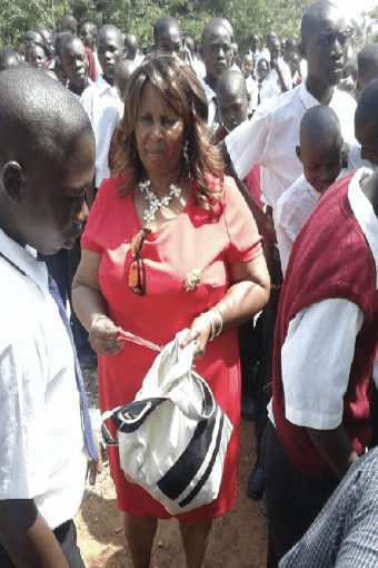 A woman in a red dress is standing in front of a group of children.