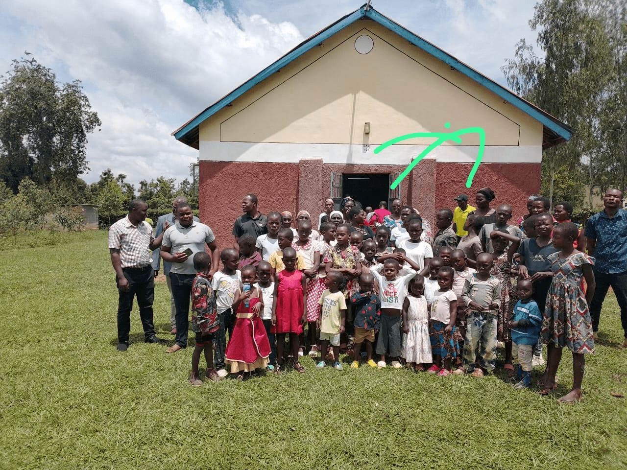 A group of school children posing in front of a house.